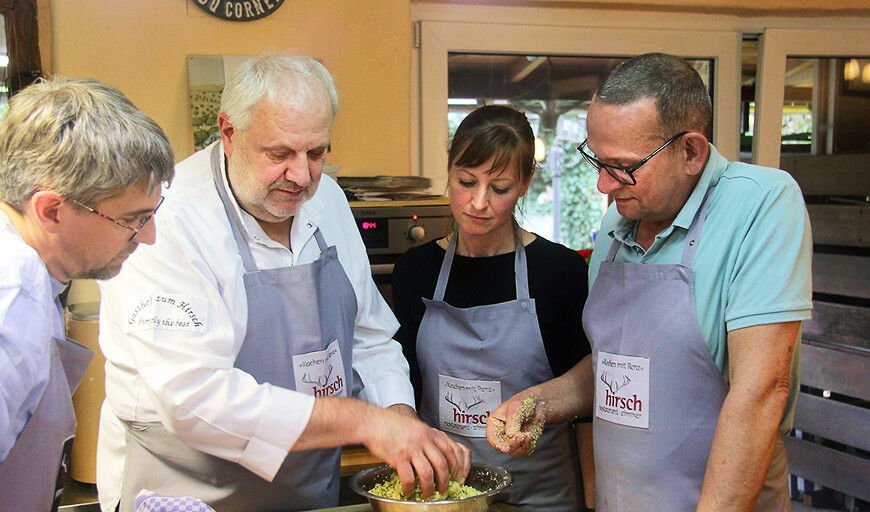 Drei Männer und eine Frau kochen.