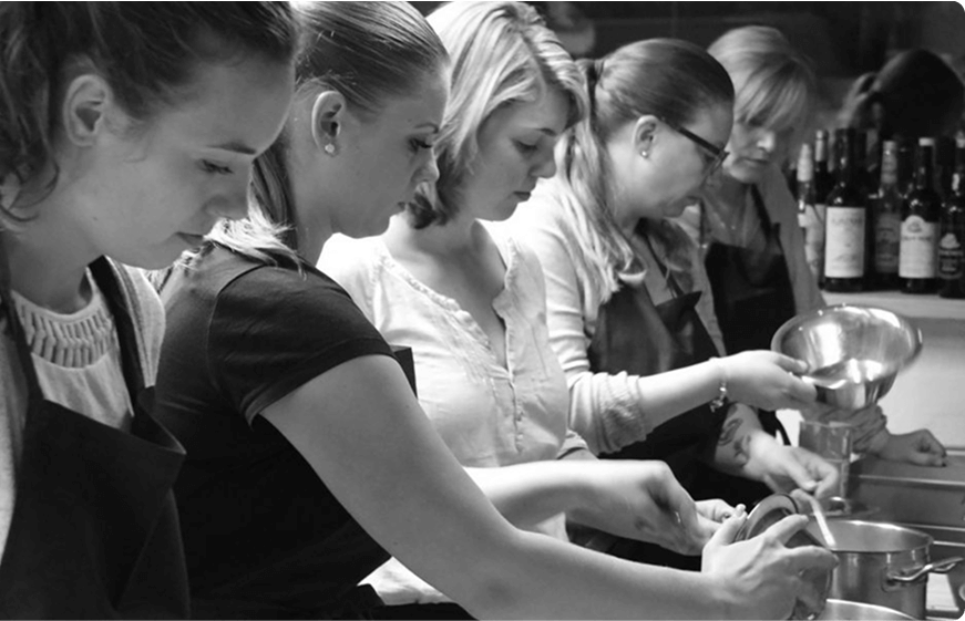 Eine Gruppe von Frauen kocht gerade zusammen.